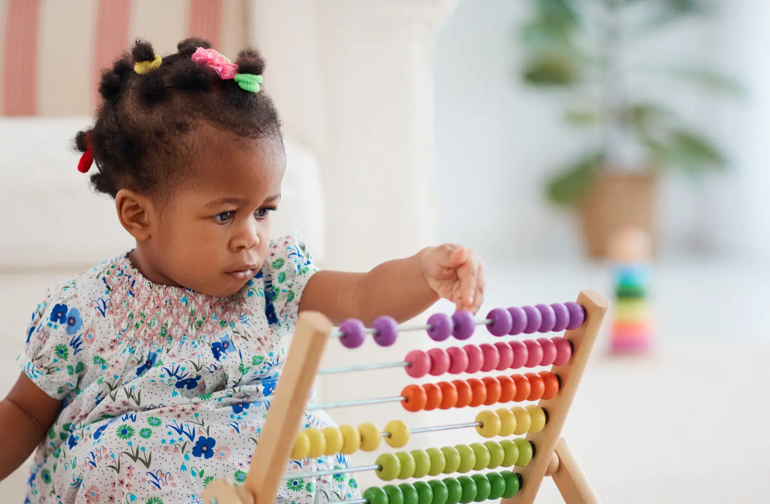 Süßes afroamerikanisches Mädchen, das zu Hause buntes Abakusspielzeug spielt